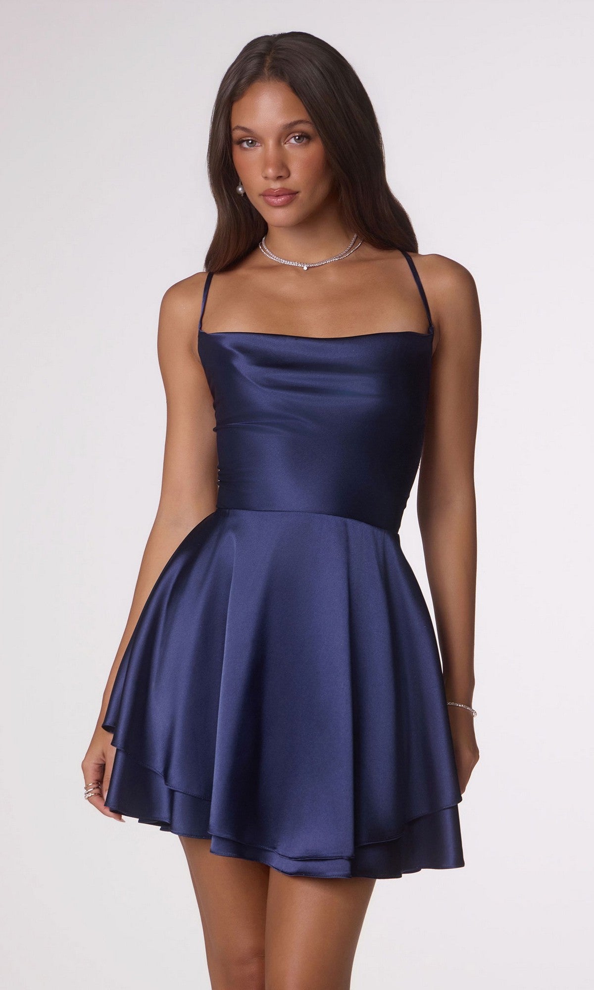 A woman wearing the Amoris T616 short navy satin homecoming dress with thin straps and an open back stands against a plain light background.